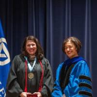 Provost Mili smiles with woman holding red gift box